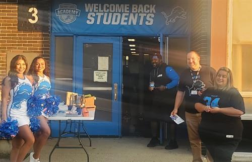  5 people standing at the door to welcome students to school with Lions giveaways